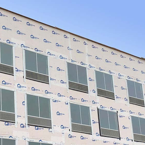 Barricade house wrap covering a large commercial building with multiple windows