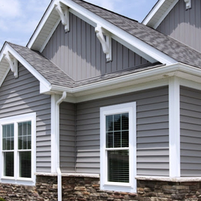 Vinyl siding on modern gray home with white trim and black roof. The vinyl siding is paired with a brick veneer on the lower half of the facade.